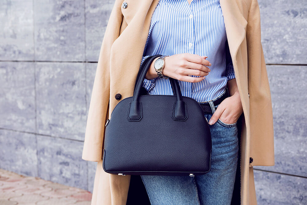 Trendy woman in beige coat with black big bag